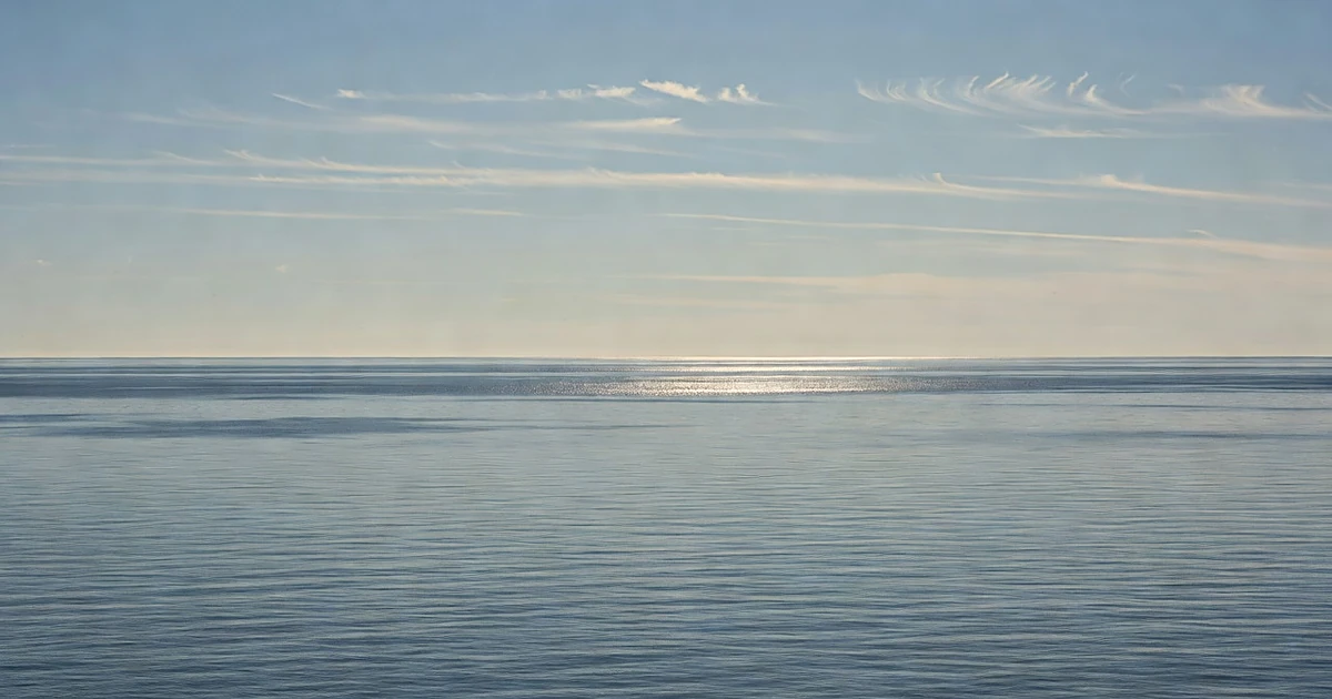 Wide view of calm Atlantic Ocean under clear blue sky with gentle swells and no storm activity visible