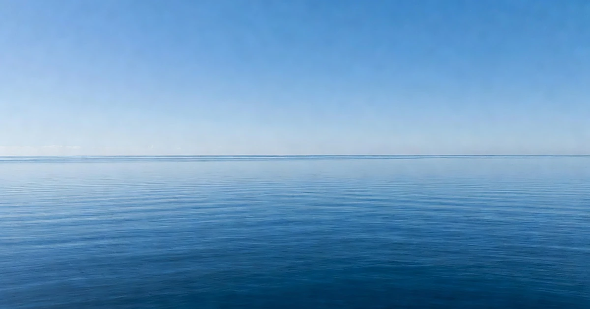 Calm Atlantic Ocean surface under clear blue sky showing no storm activity or wave disturbance