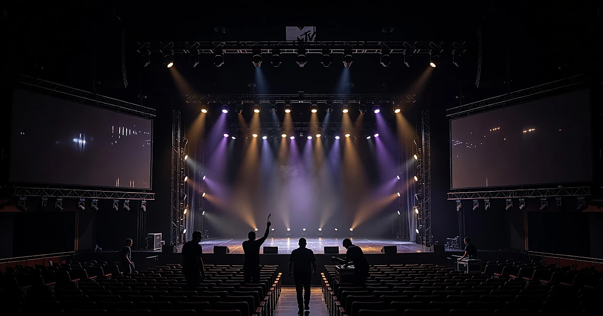 Empty concert stage with lighting rigs and crew silhouettes preparing for a major music awards show performance
