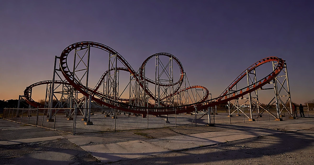 Empty roller coaster track with twisted steel rails and vertical loops photographed at dusk