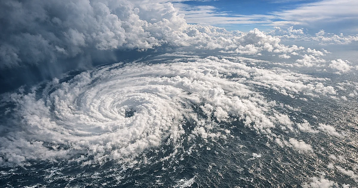 Aerial view of tropical storm system with spiral cloud bands churning over dark Atlantic Ocean waters
