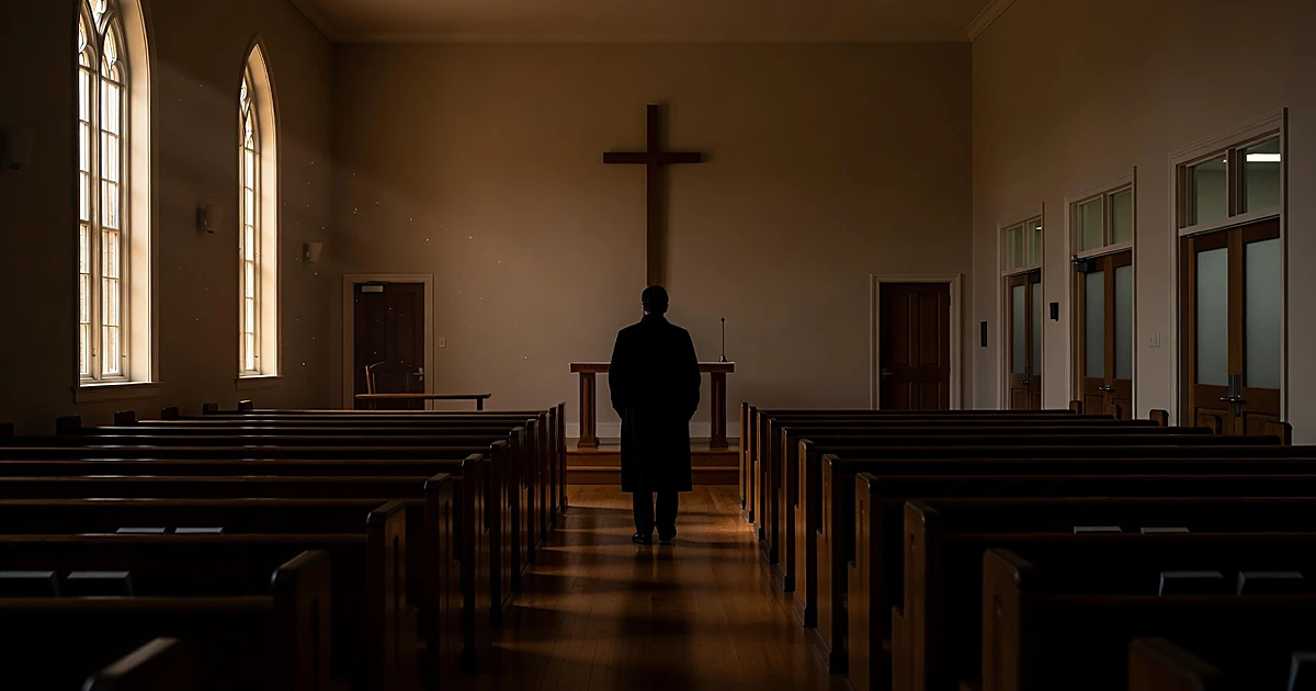 Empty university chapel interior with silhouetted figure standing in aisle between pews and administrative offices