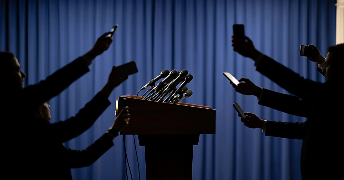 White House press briefing room with reporters' arms holding microphones extended toward presidential podium