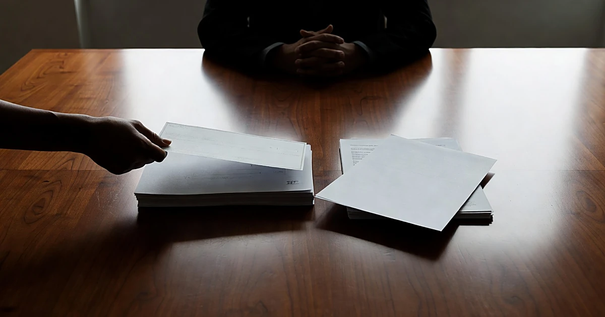 Campaign contribution check and documents being passed across boardroom table between silhouetted figures