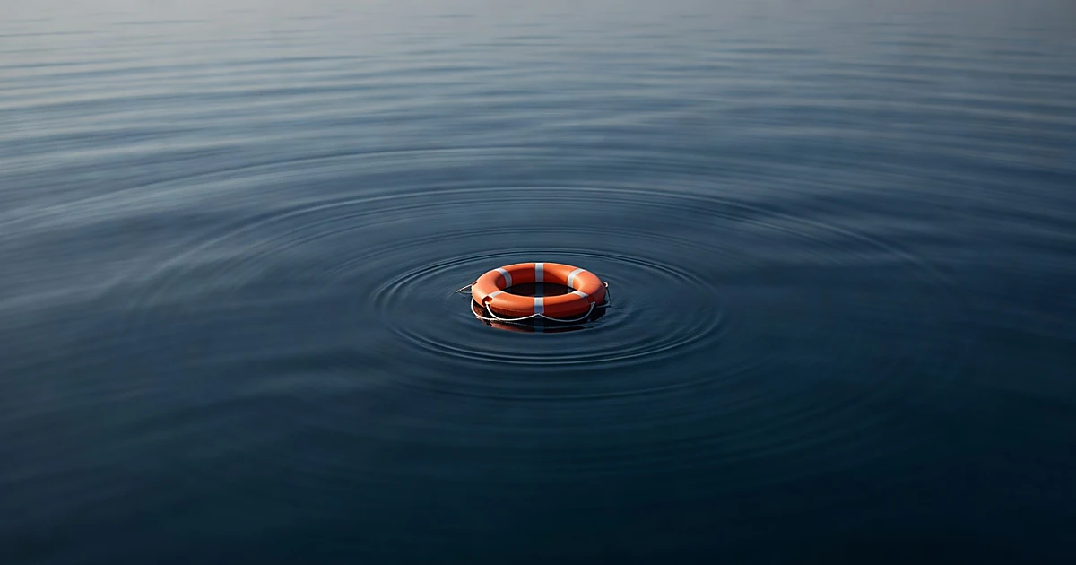 Orange life ring floating alone on dark blue ocean water surface with gentle ripples
