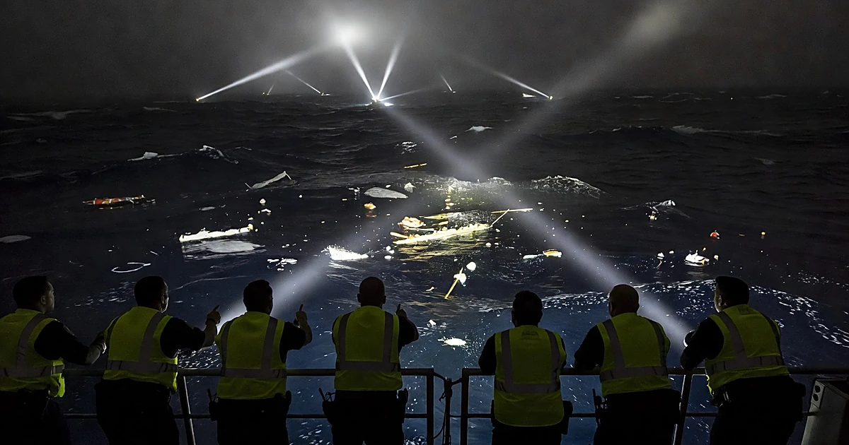 Coast Guard crew silhouettes searching dark Atlantic waters with searchlights illuminating scattered debris at night