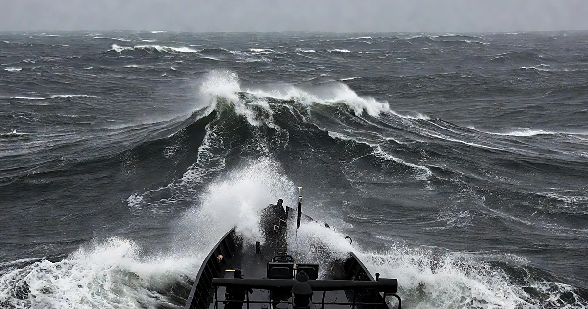 Coast Guard vessel navigating massive storm swells in the Atlantic Ocean under dark threatening skies