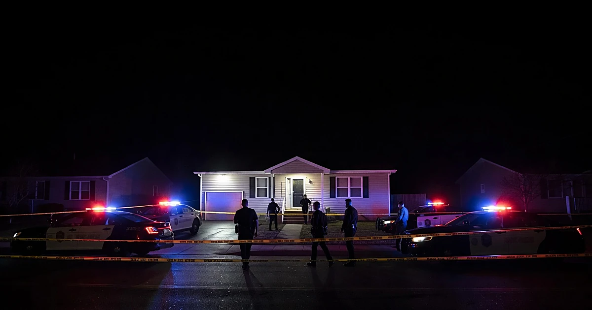Police emergency lights illuminate residential home at night during active investigation on neighborhood street