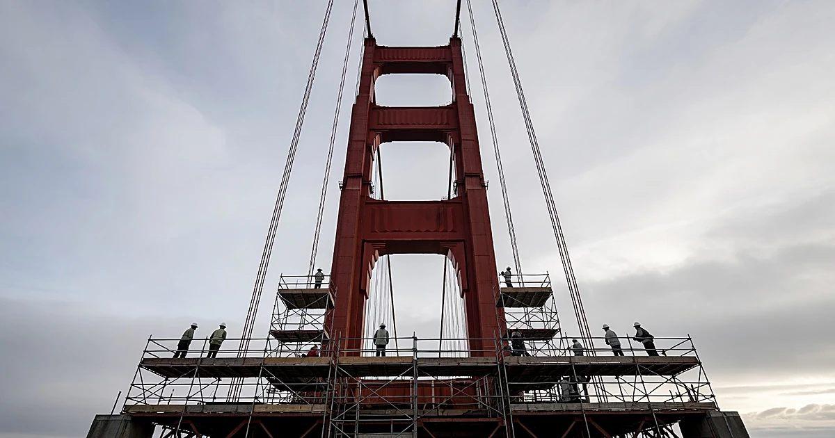 Construction workers on scaffolding beneath Golden Gate Bridge tower during seismic retrofit work