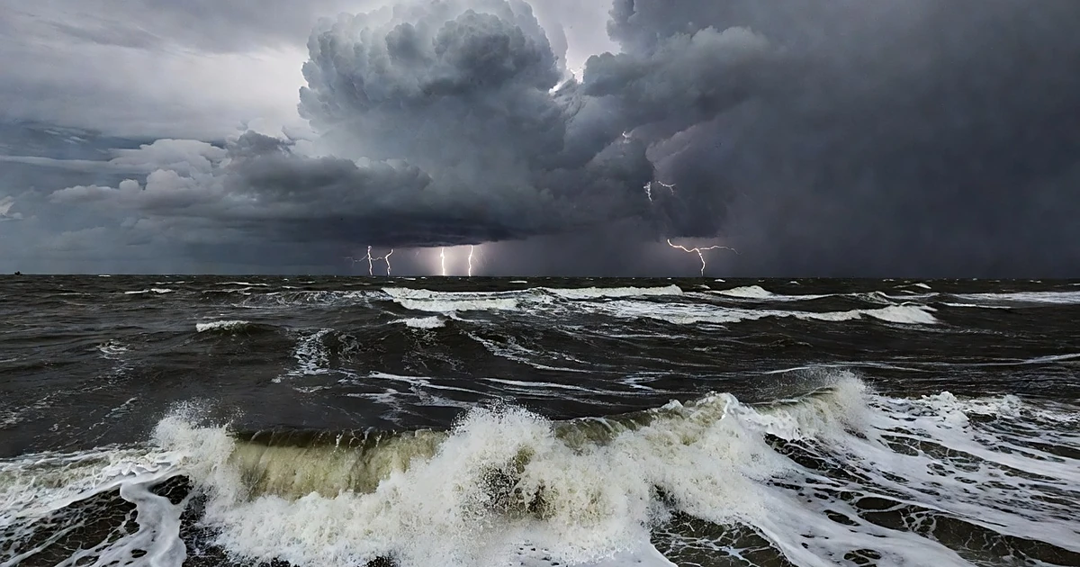 Dark storm clouds gather over churning Gulf waters with violent waves and distant lightning on the horizon