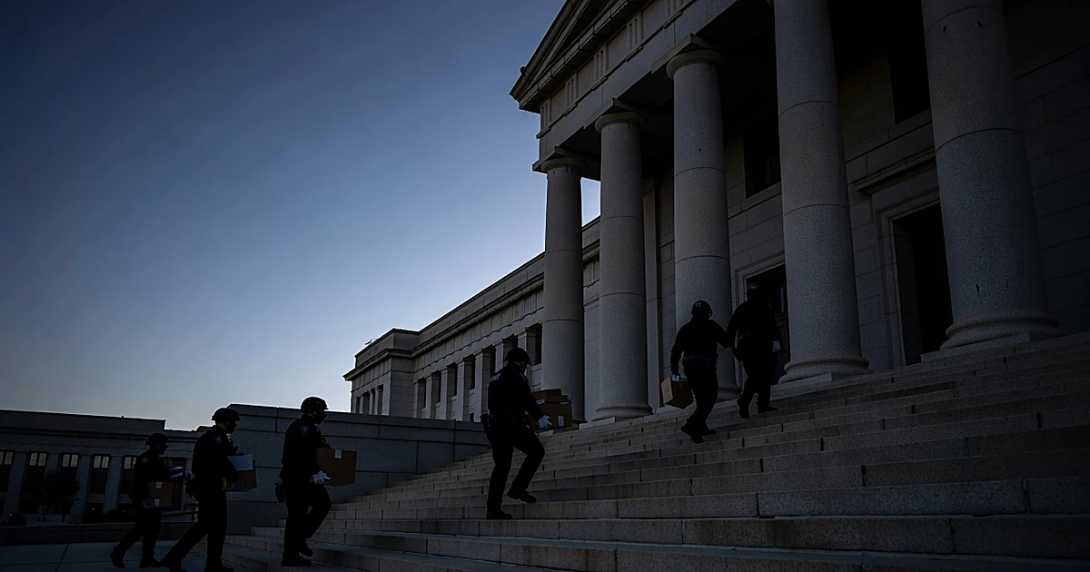 Federal agents in silhouette ascending government building steps at dawn with document boxes