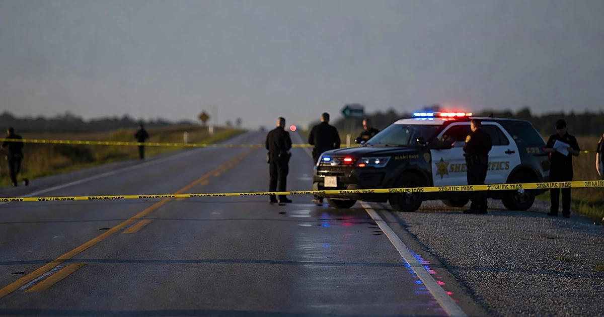 Sheriff patrol car with emergency lights on deserted roadway at dawn with crime scene tape in foreground