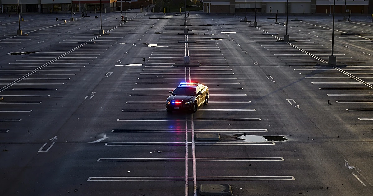 Police car with flashing lights in empty parking lot at dusk