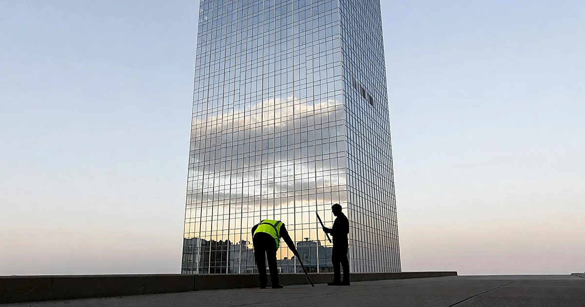Silhouetted volunteers on sidewalk at base of reflective glass skyscraper at dawn in downtown Chicago