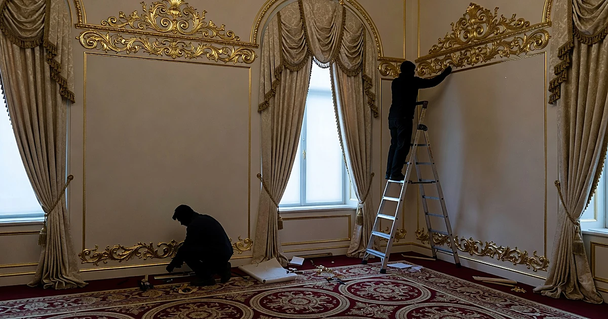 Workers installing ornate gold rococo trim in presidential office replica with burgundy carpet and cream walls