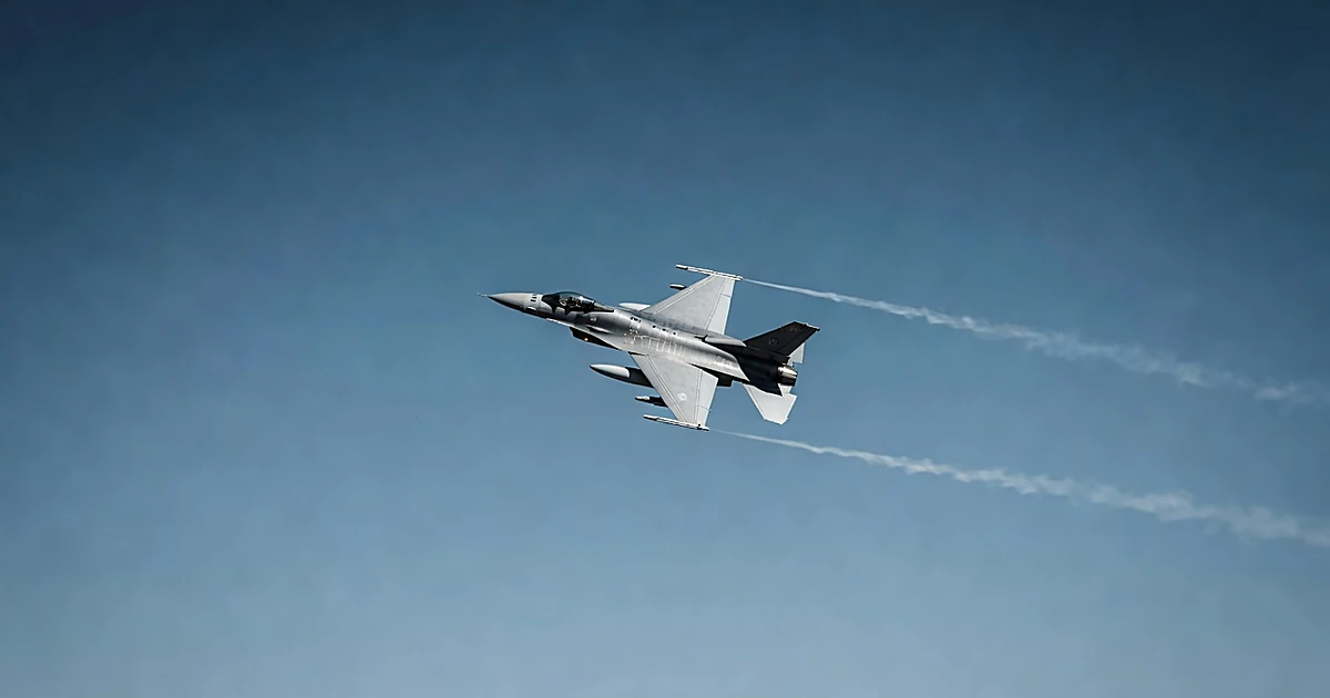 Military F-16 fighter jet in flight against clear blue sky during daytime intercept operation