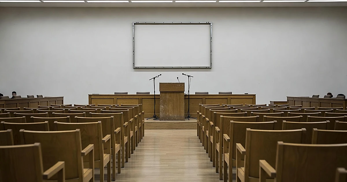 Empty government meeting chamber with podium and vacant wall mount behind speaking area