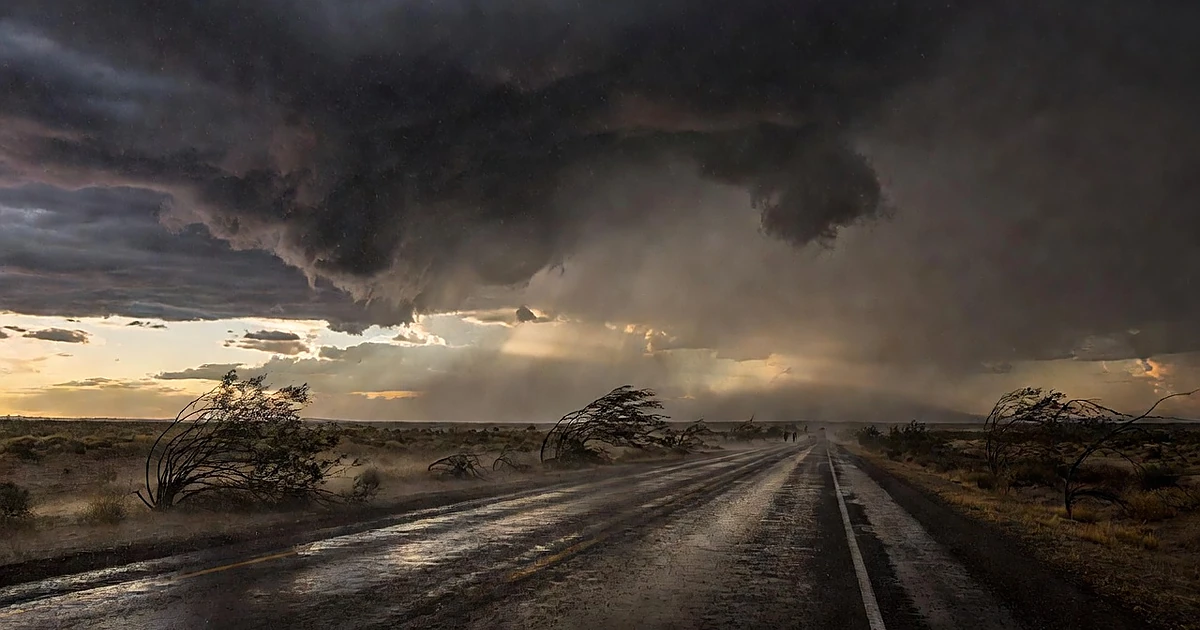 Storm clouds and heavy rain approaching across a desert highway in the Southwest at dusk