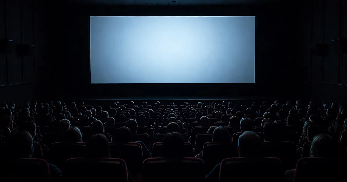 Silhouetted audience members in darkened movie theater facing large illuminated cinema screen