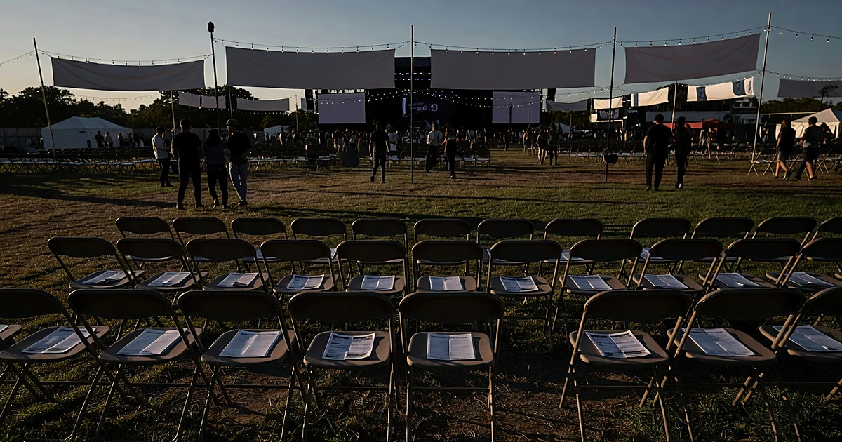 Empty festival chairs with campaign materials at outdoor music venue during golden hour with silhouetted crowd