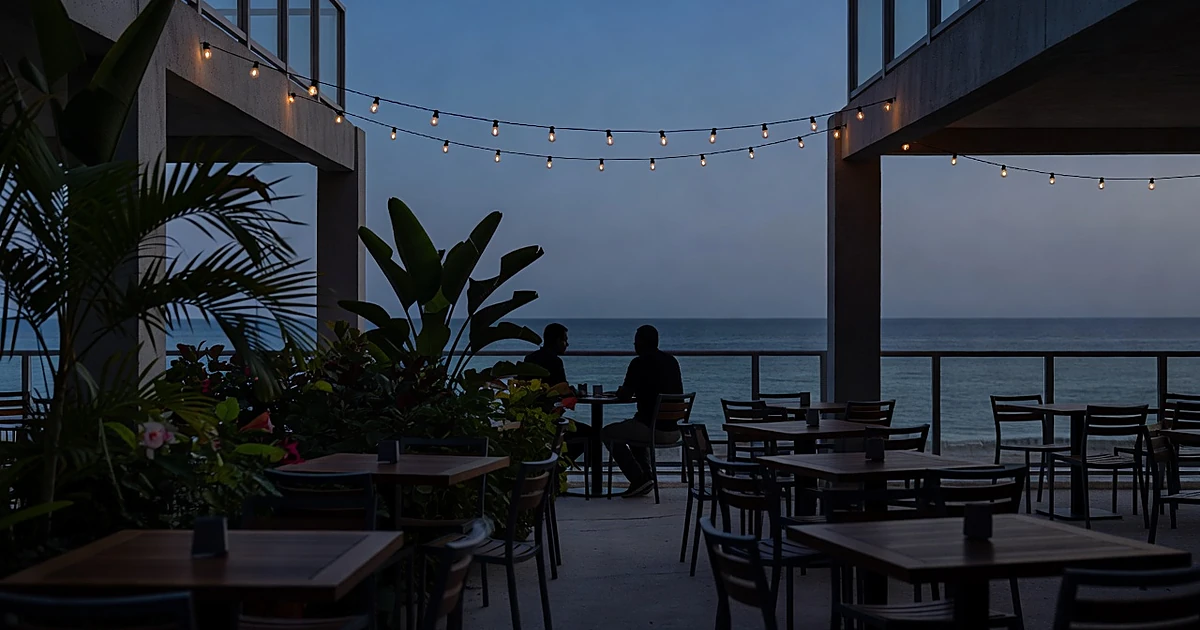 Silhouetted figures at secluded Miami beachfront restaurant table at dusk with ocean view