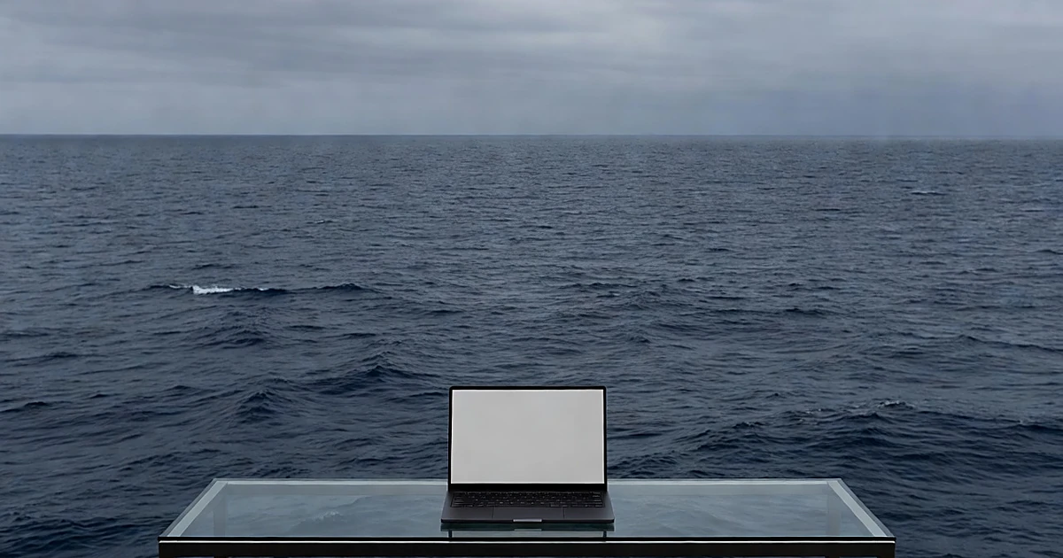 Laptop computer on glass desk overlooking vast Atlantic Ocean under overcast sky